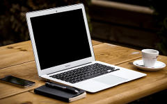 Apple MacBook computer on a table with a coffee cup